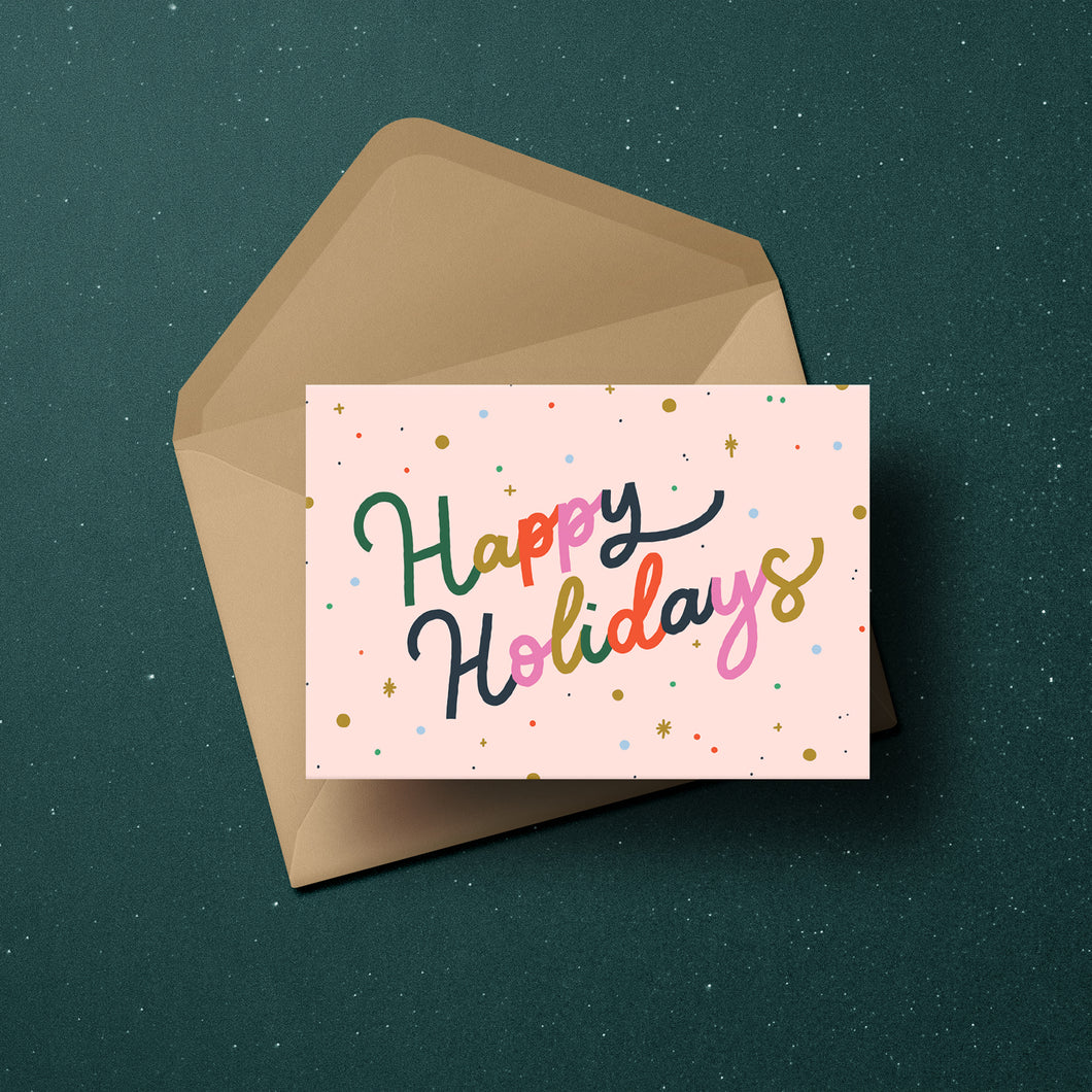 'Happy Holidays' in colourful lettering surrounded by confetti and merry little stars, set against a blush background.