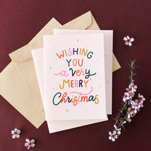 Load image into Gallery viewer, Wishing You a very Merry Christmas in colourful lettering surrounded by merry little stars, set against a blush background
